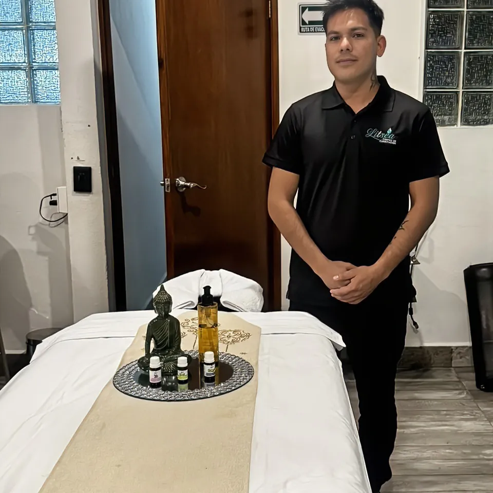 Terapeuta de Litsea junto a una cabina de masaje preparada con aceites esenciales