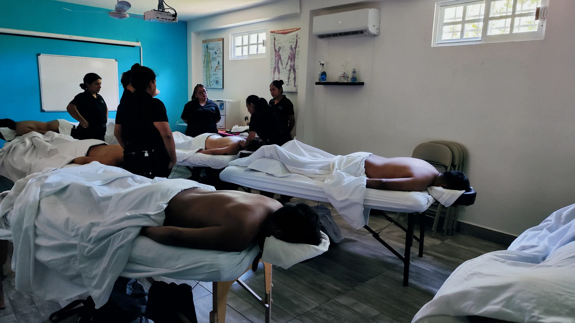 Clase práctica de masoterapia con camillas ocupadas en Litsea
