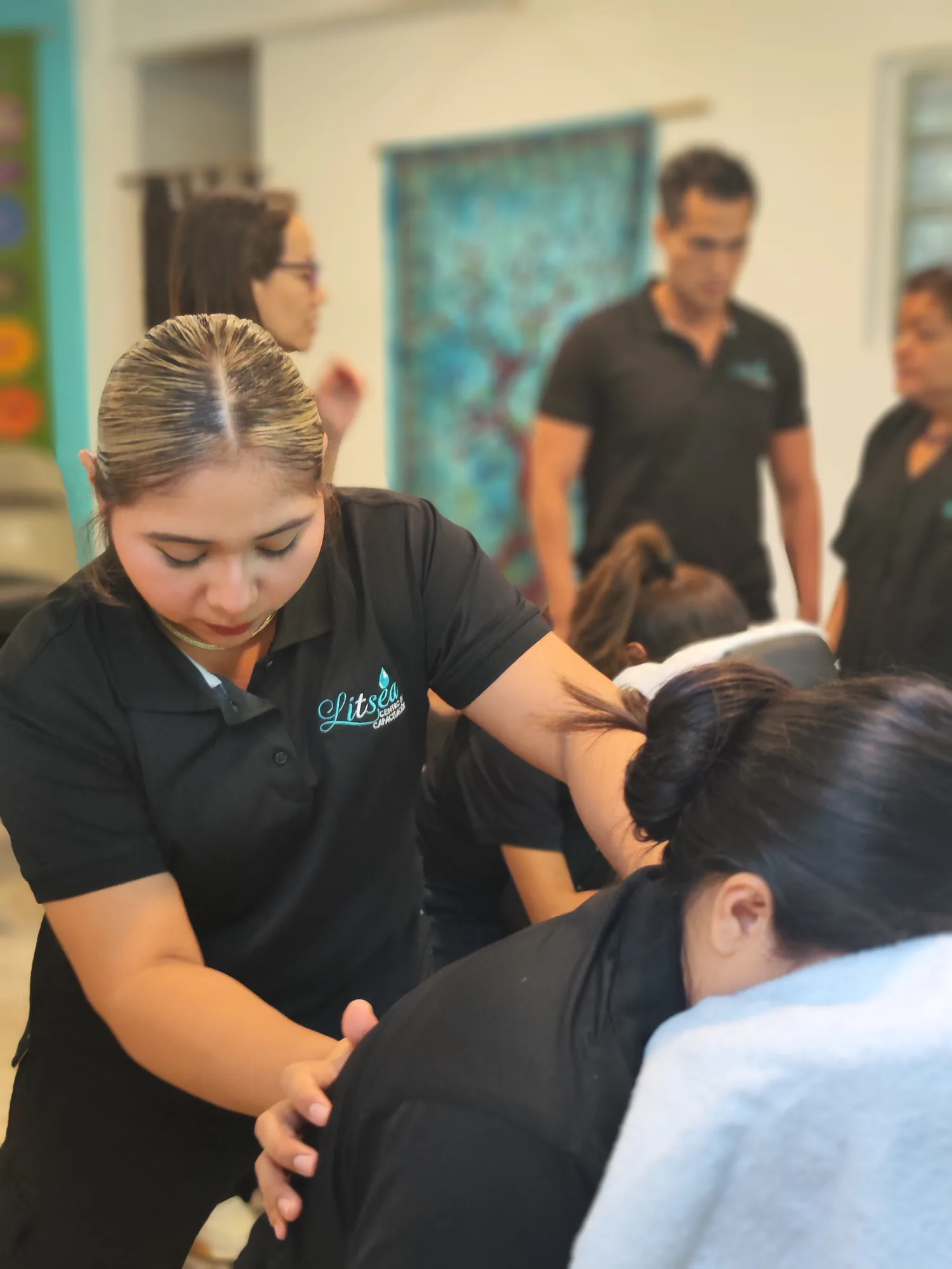 Alumna de Litsea practicando masaje de cuello y hombros con supervisión docente